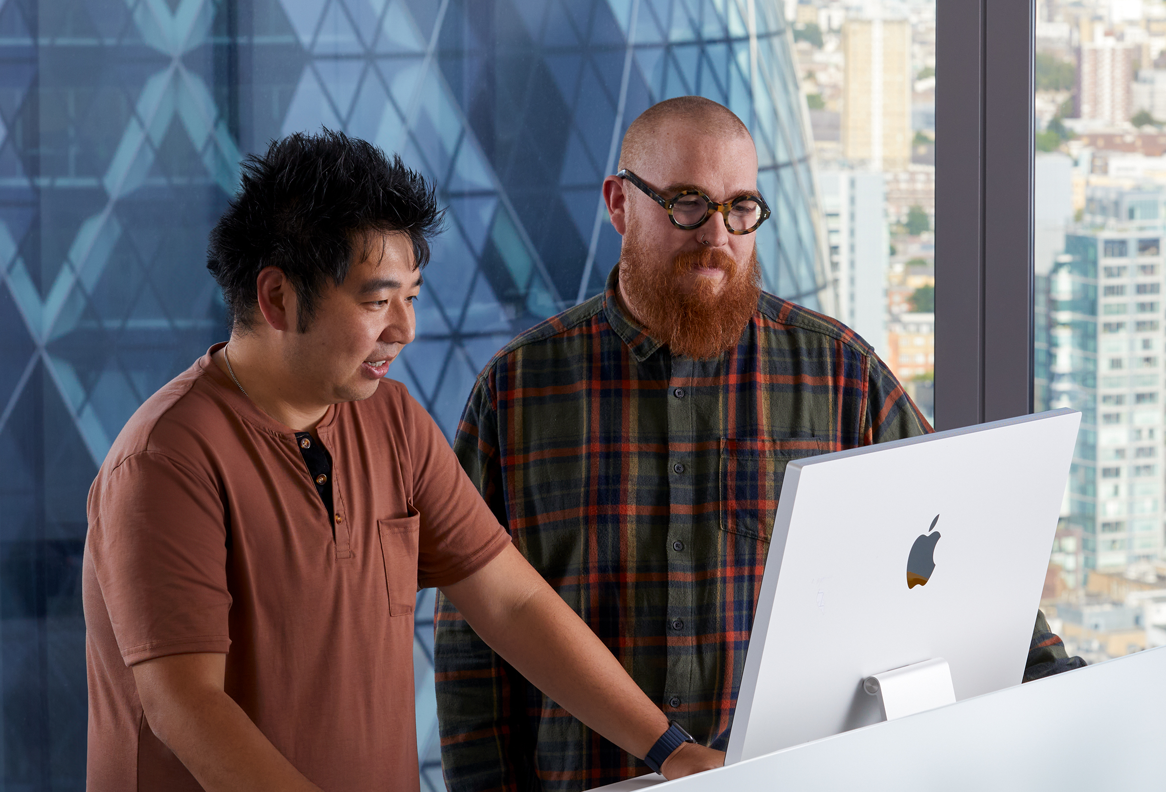 Zwei Apple Kollegen arbeiten zusammen an einem iMac.