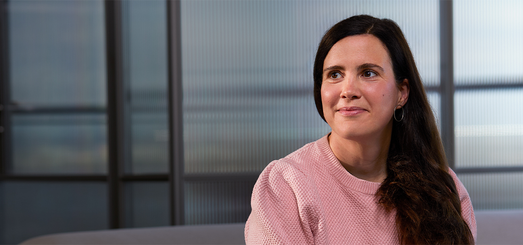 Lucie sitzt drinnen, hinter ihr eine Glaswand. Sie lächelt und schaut nach rechts.