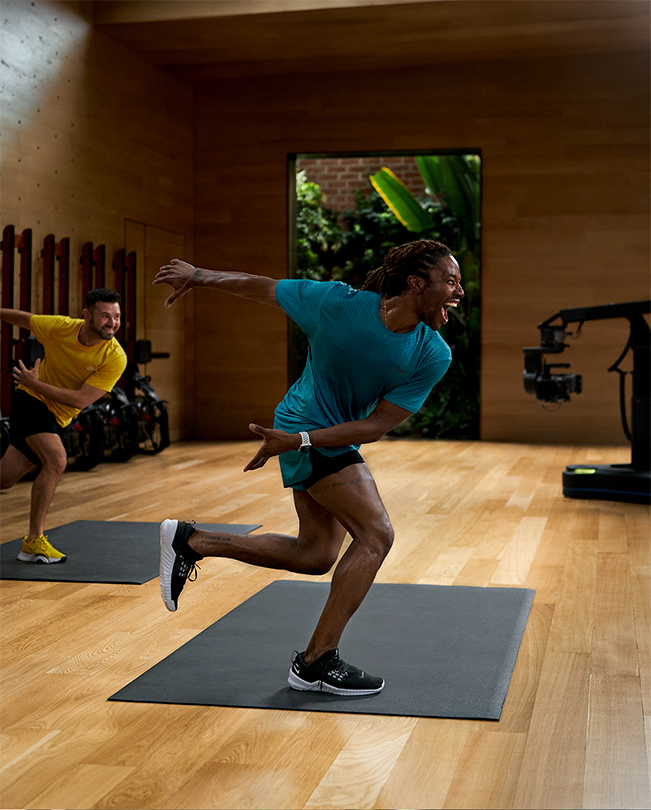 Entrenadores de Apple Fitness+ impartiendo una sesión delante de una cámara en un estudio de grabación. 