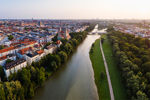Aerial view of Munich with a river, trees and a walking path alongside the river.