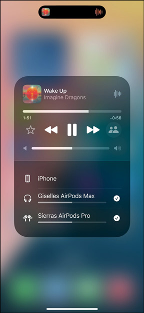 AirPods Pro im Ladecase neben dem iPhone. Das iPhone ist mit zwei Paar AirPods verbunden, die jeweils eine individuelle Lautstärkeregelung haben.