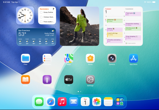 三款型號的 iPad 橫向放置，放在中間的一部位於另外兩部 iPad 的前方。Apple Pencil 以磁力貼合在中間那部 iPad 的頂部，其主畫面展示 Liquid Glass 效果的彩色 app 圖像。位於左邊的 iPad 螢幕正展示預覽程式 app，而右邊的螢幕則展示主畫面，多個檔案從 Dock 上以扇形垂直展開