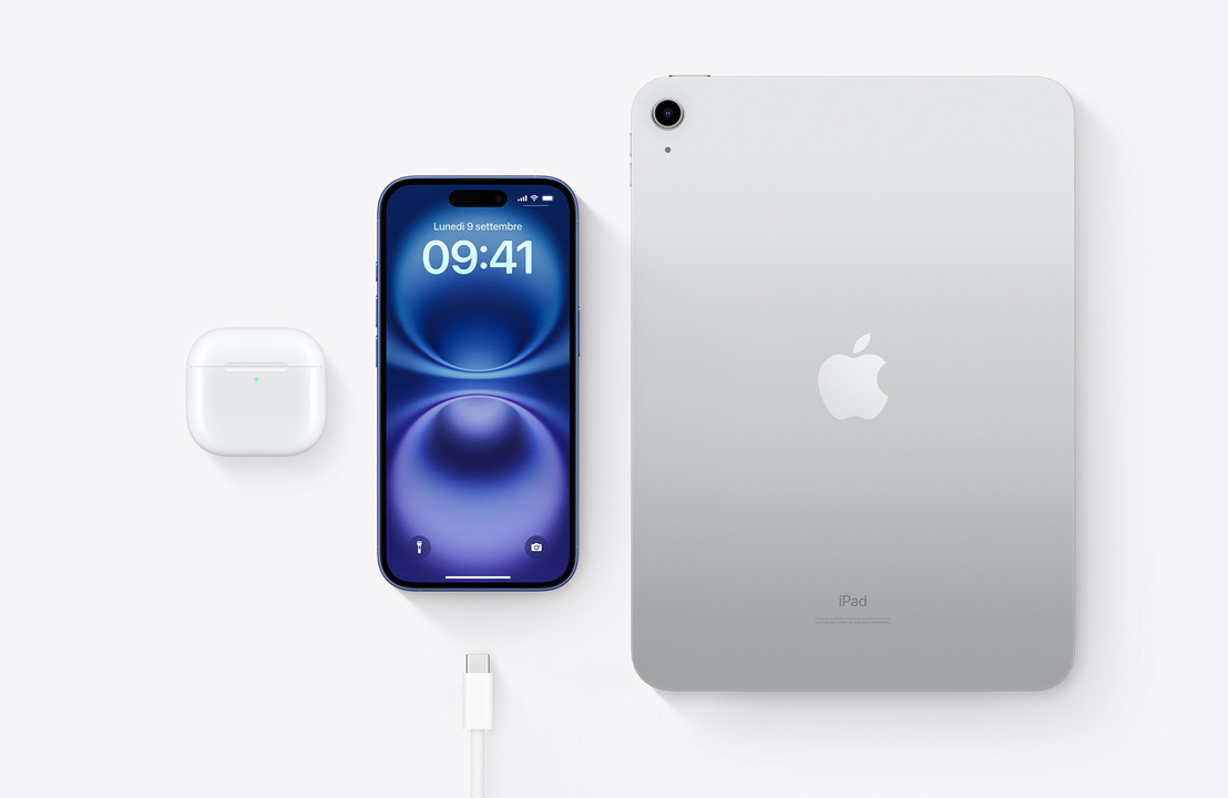 Un paio di AirPods Pro nella custodia di ricarica, un iPhone 16, un iPad e un cavo con connettore USB-C, per mostrare che tutti e tre i dispositivi si possono caricare con lo stesso cavo USB-C.