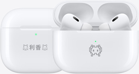 絵文字の例が刻印された2つのAirPods 4の充電ケース。1つには「利香」というテキストの両側に猫の絵文字が刻印され、もう1つにはカニの絵文字が刻印されている