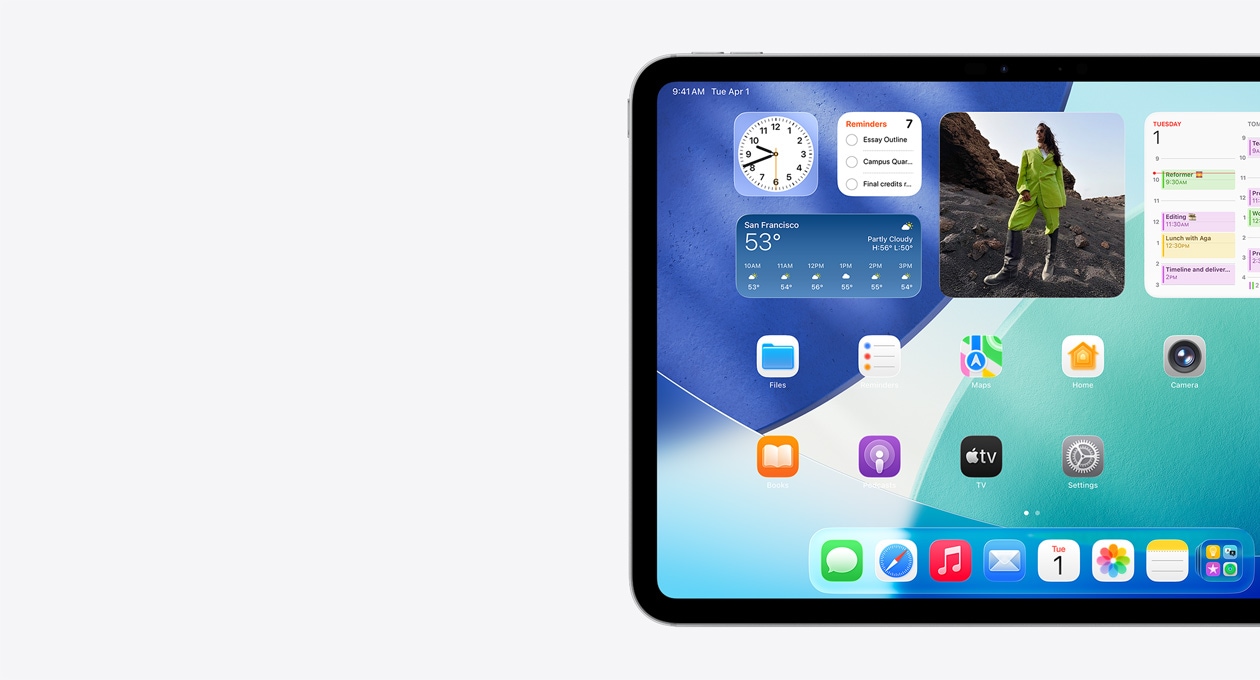 iPad في الوضع الأفقي، ويظهر الجانب الأيسر من الشاشة فقط، حيث أن الشاشة الرئيسية تتضمن الأدوات المكدسة بما فيها الساعة الشفافة التي تعرض تأثير Liquid Glass، وتطبيق تحديد الموقع، وأداة الطقس، وصفين من التطبيقات الأصغر، وشريط الأيقونات