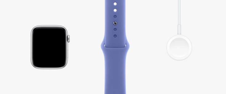 Colocados en fila: parte frontal del hardware de un Apple Watch SE, una correa deportiva violeta azul y un cable de carga magnética con conector USB-C.