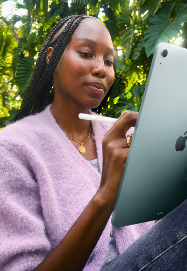Une étudiante assise dehors. Elle tient un iPad et un Apple Pencil Pro.
