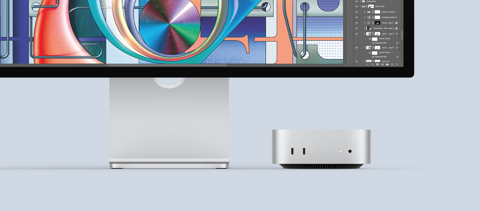 Vista frontal de una Mac mini color plata con puertos delanteros y luz de encendido, que se acomoda perfectamente debajo de un monitor Mac con una pantalla colorida