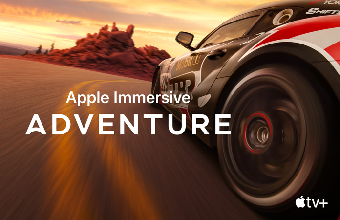 달리고 있는 경주용 차와 그 위에 하얀색 글씨로 Apple Immersive Adventure라고 적힌 문구