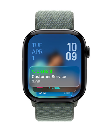 Apple Watch en negro azabache con una correa deportiva color salvia, cuya carátula muestra una notificación de Asistente Telefónico en la parte inferior, la fecha en la parte superior, con números angostos en la esquina superior derecha