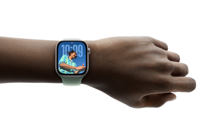 Se ve la muñeca de una persona con un Apple Watch color plata y una correa de goma, con una carátula que muestra la app Notas y un mensaje